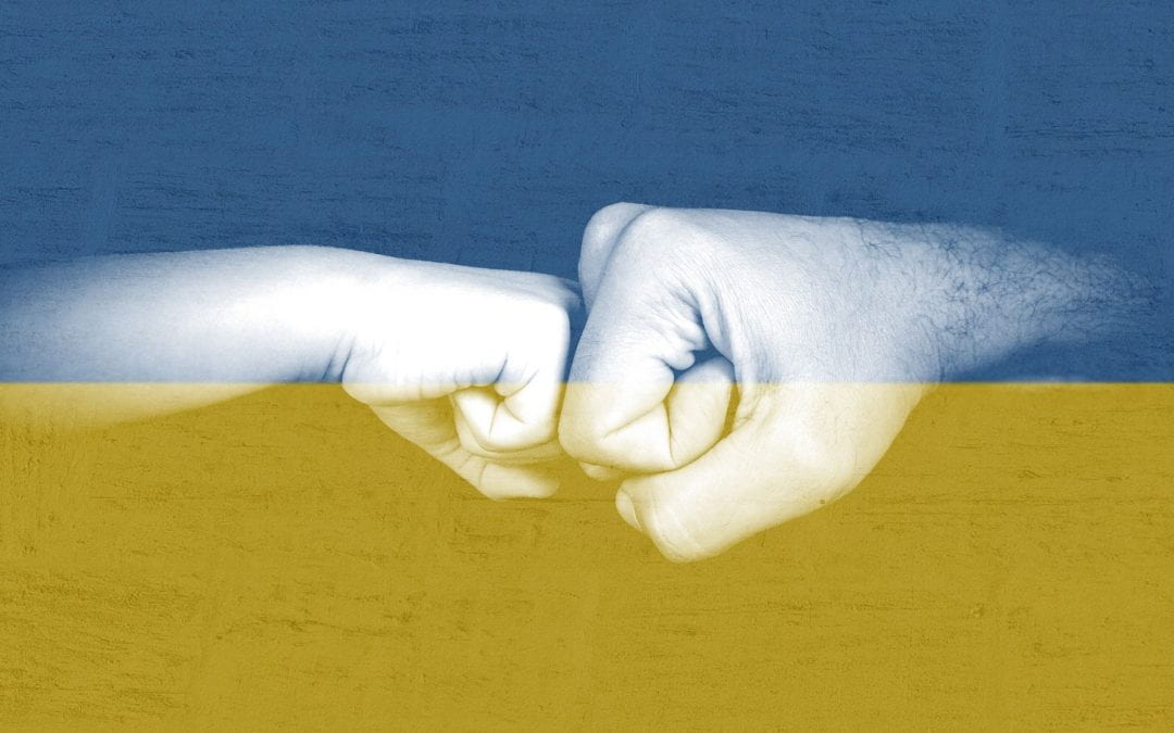 two hands fistbump over Ukrainian flag